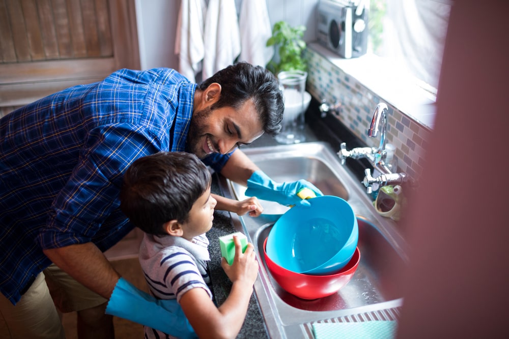 Child doing washing up with father