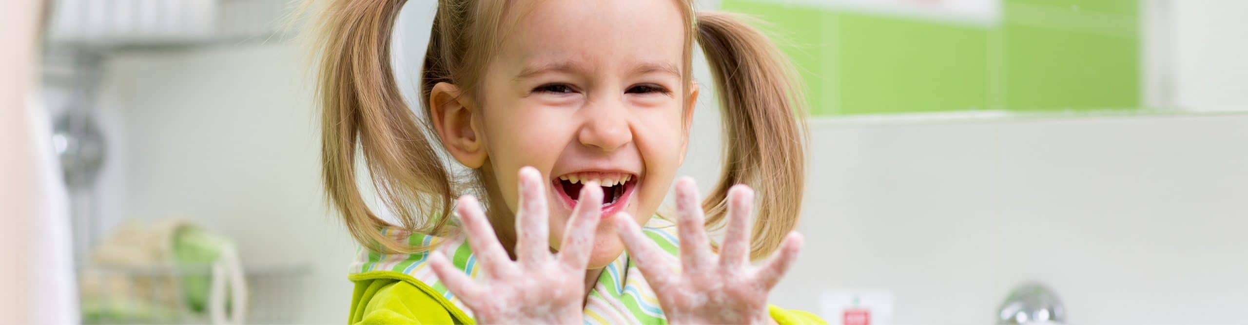 Child holding up her soapy hands.