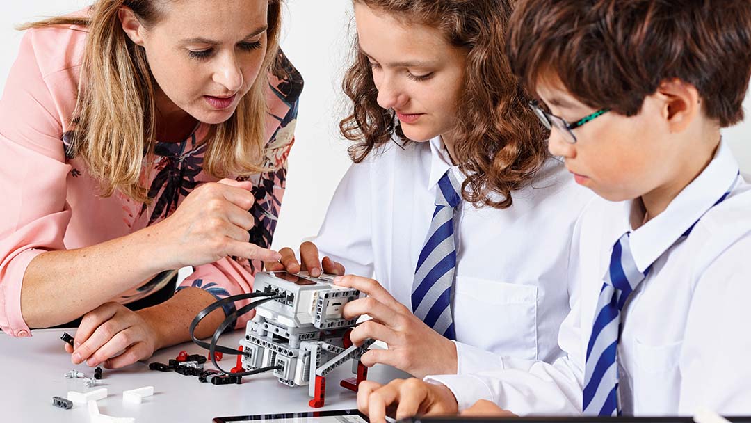 Three children learning to code with teacher