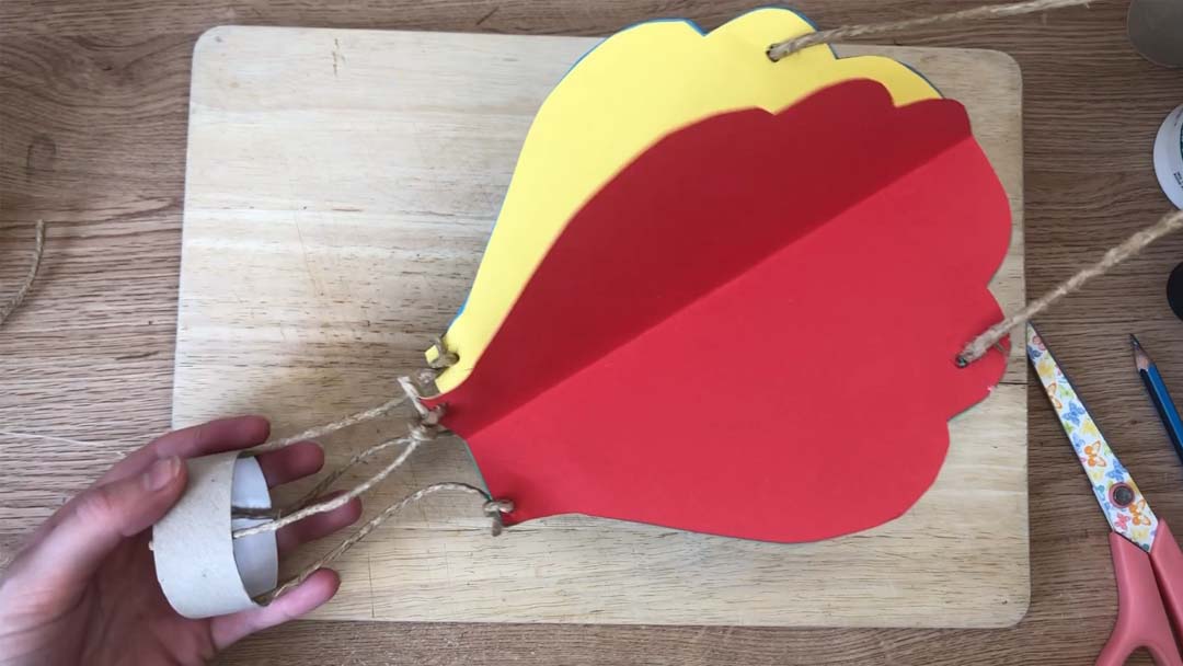 Homemade hot air balloon craft on a wooden chopping board.