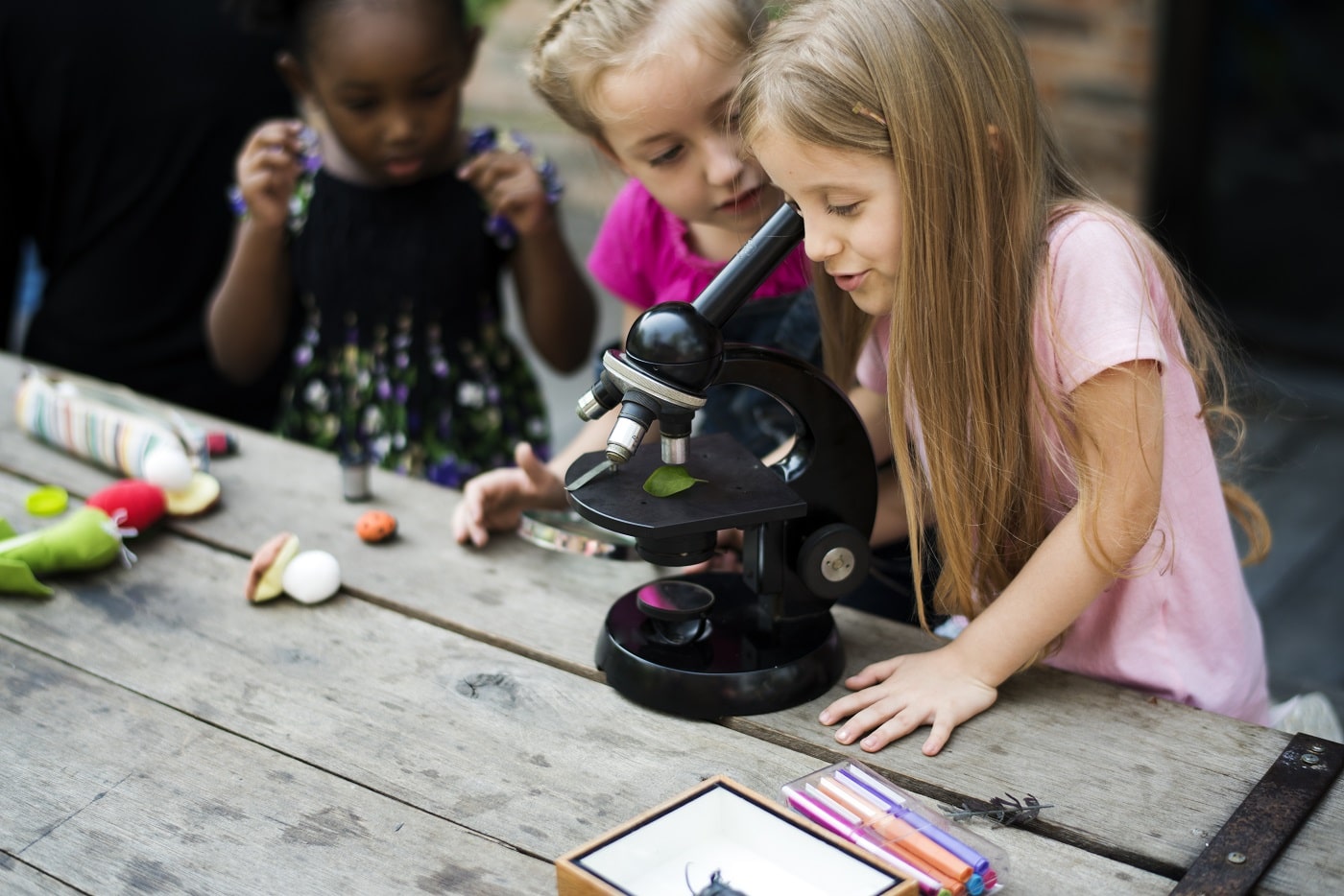 school children use microscope outdoors