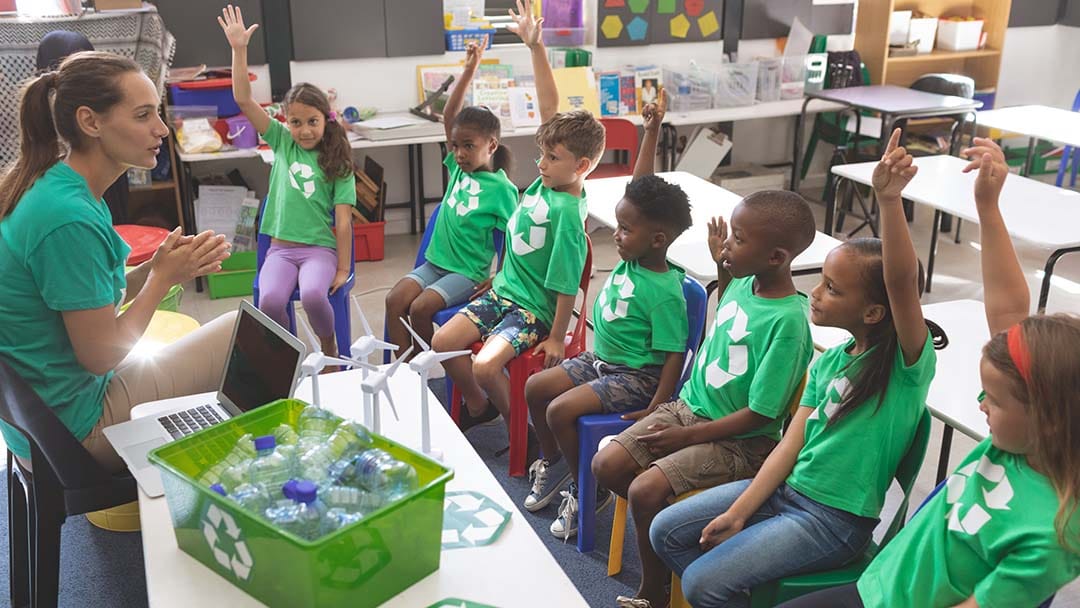 Teacher showing class of children how to recycle