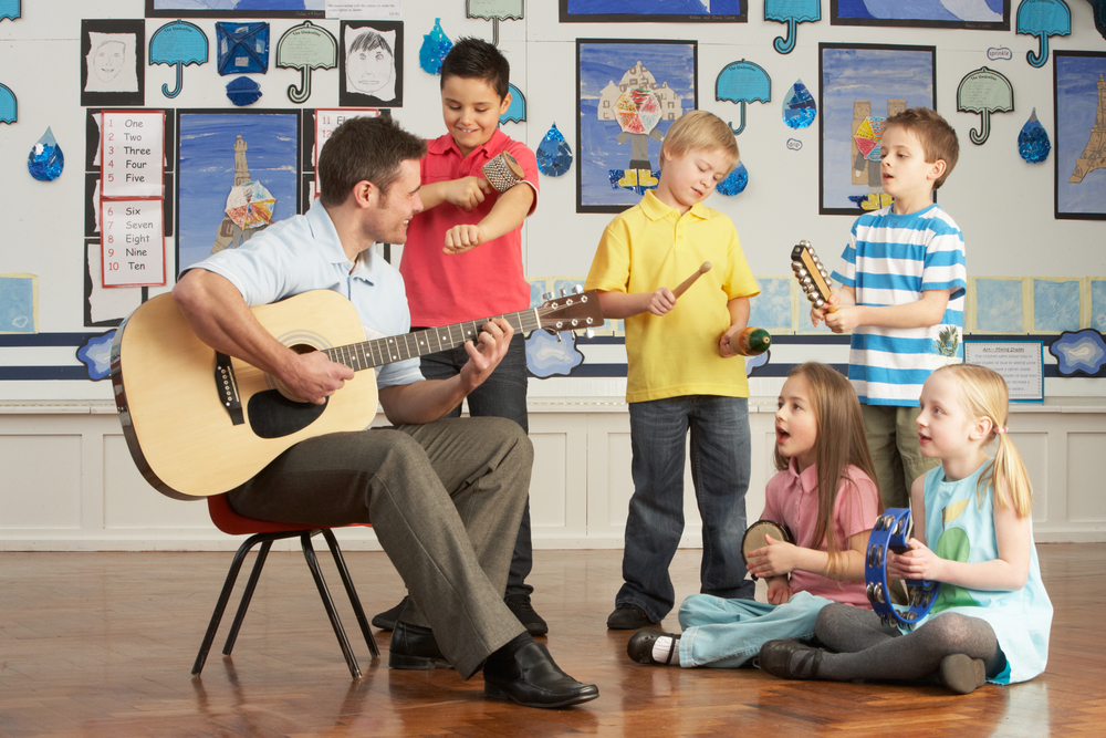 Benefits of learning an instrument- teacher and pupils playing instruments together 