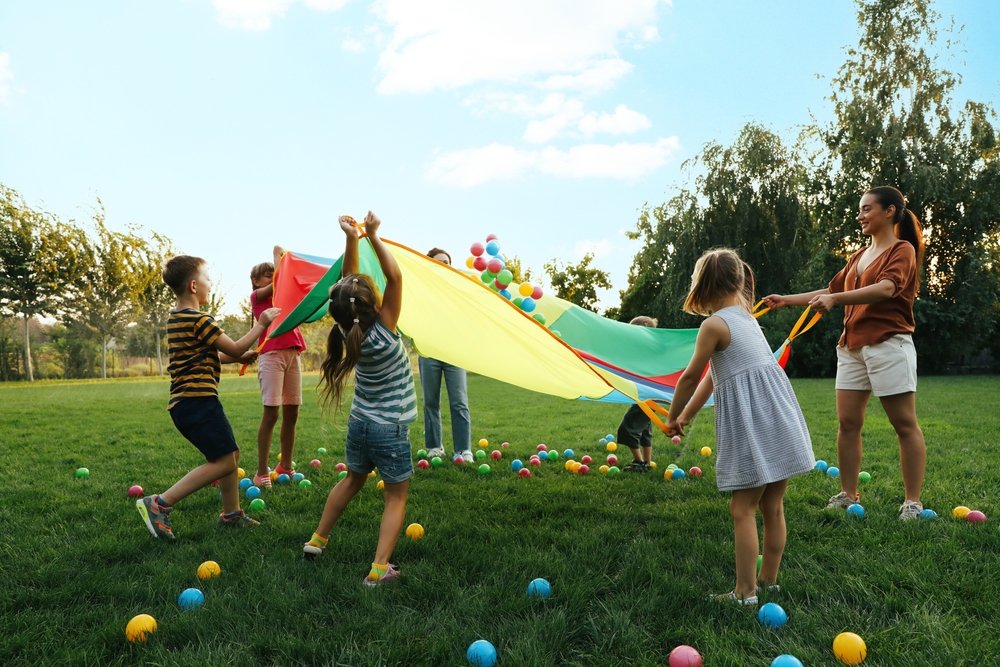 Incorporate cross curricular outdoors- children playing with parachute science
