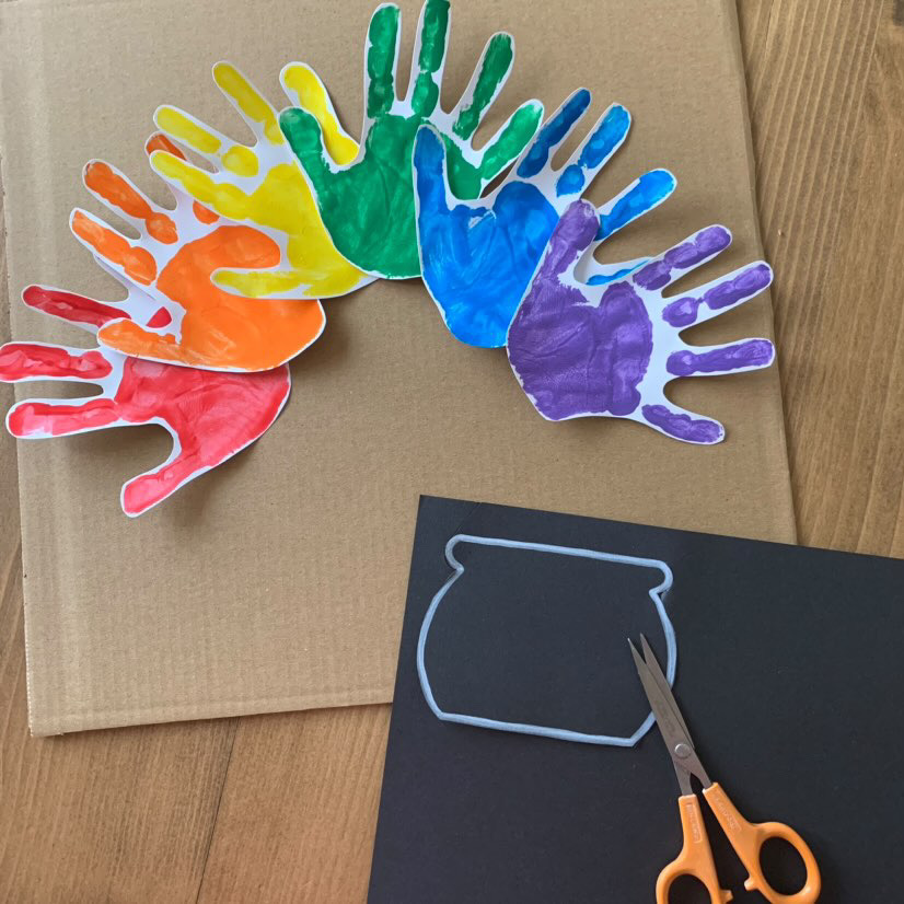 cutting out pot shape and sticking rainbow handprints onto card