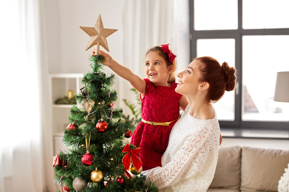 child hanging star on christmas tree